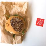 Panino con hamburger, pomodori secchi, rucola e mandorle