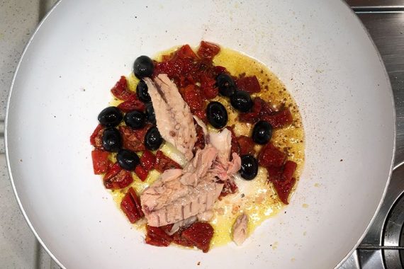 Preparazione della pasta con sugo di pomodori secchi, tonno e olive nere